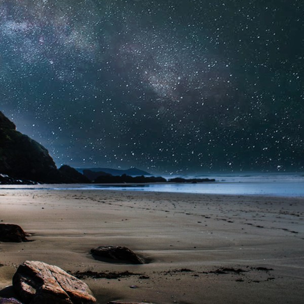 Milky Way galaxy arcs over an ocean beach at night
