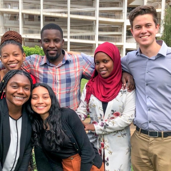 Male and female students standing outside in a group smiling for the camera