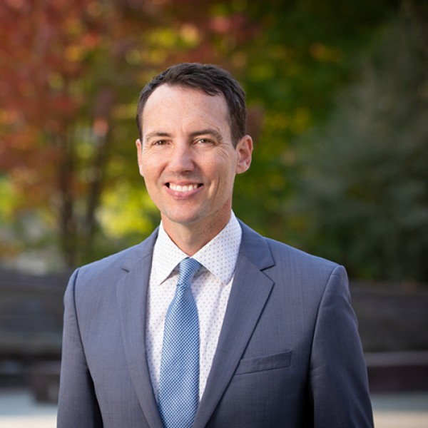 a man in a suit stands outside and smiles