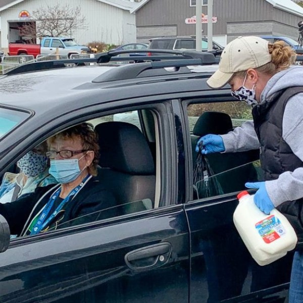 woman delivers milk to people in car