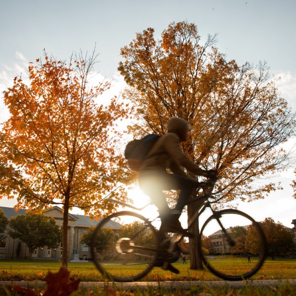 A student riding a bike in a college quad