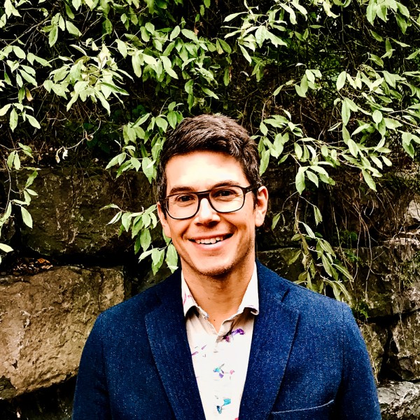 Louis Longchamps standing outside against a ivy-covered brick wall