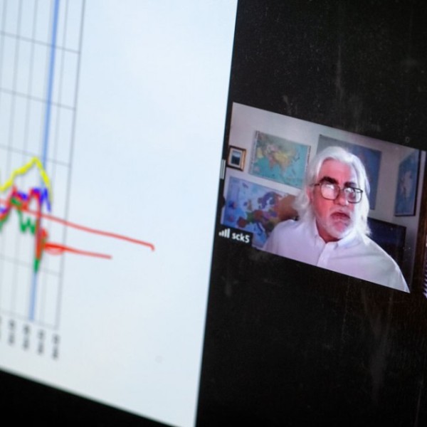 a screenshot of a Zoom screen with an economist and a graph