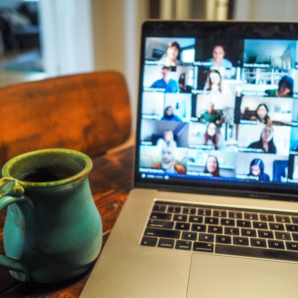 A zoom call pulled up on a laptop with a green mug next to it on the table