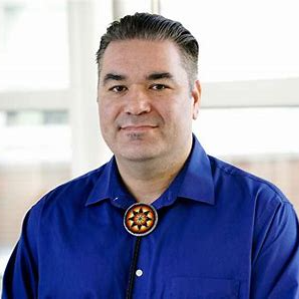 Portrait photo of man with short black hair in blue shirt.