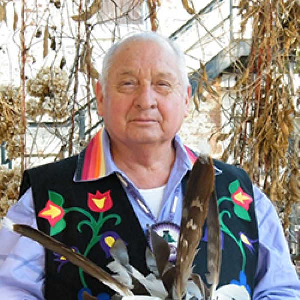 photo of man sitting with corn husks in the background