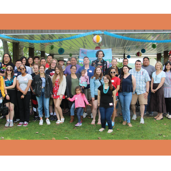 Photo of a large group posing and smiling during the summer.