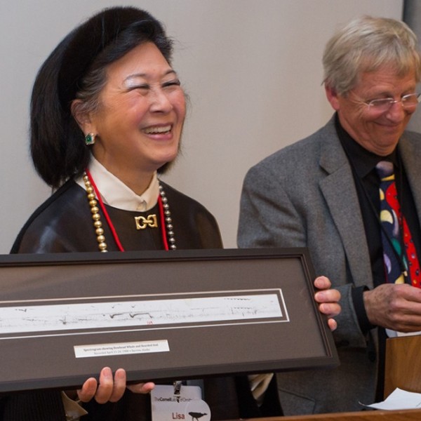 K. Lisa Yang holds a framed spectrogram of a bowhead whale recording as she stands next to Chris Clark