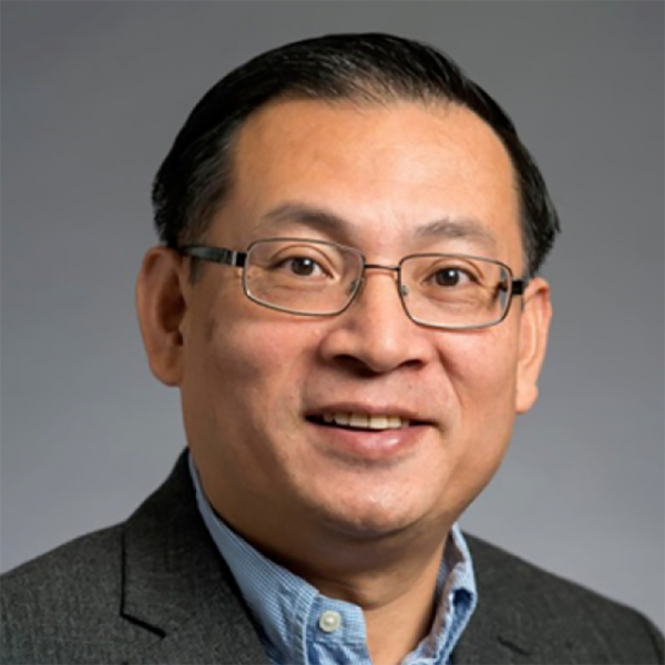 a close up of a man with glasses a blue shirt and gray jacket