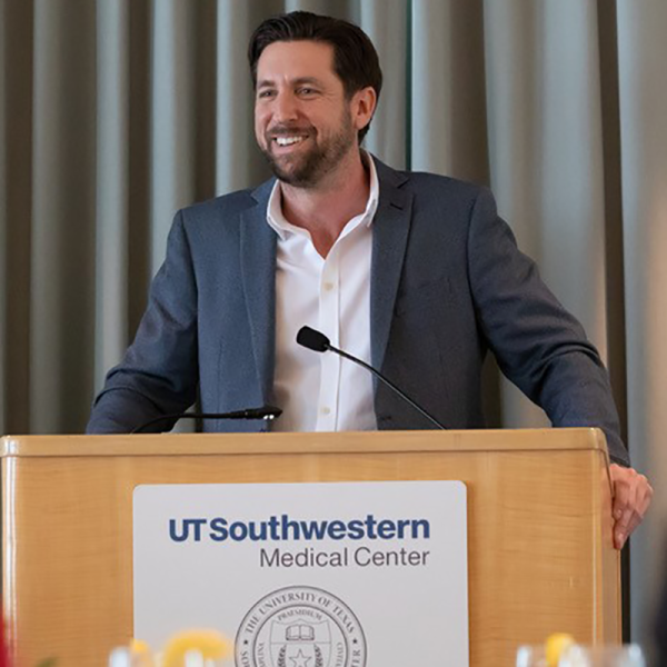 a man in a white shirt and gray jacket stands behind a podium
