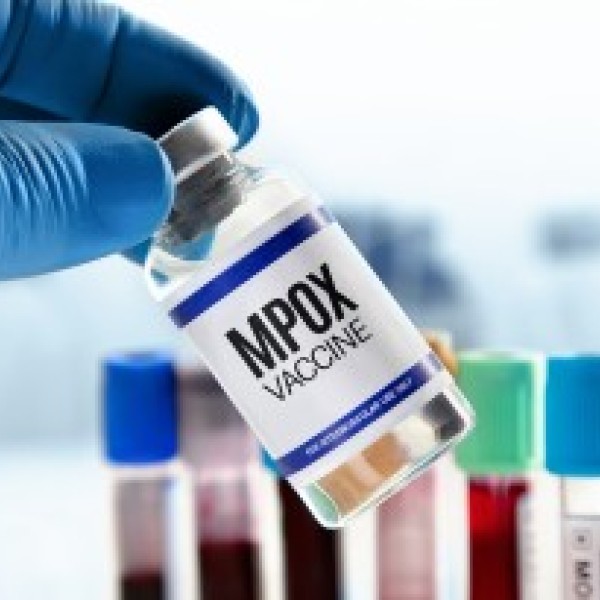 a gloved hand holding a bottle of mpox vaccine