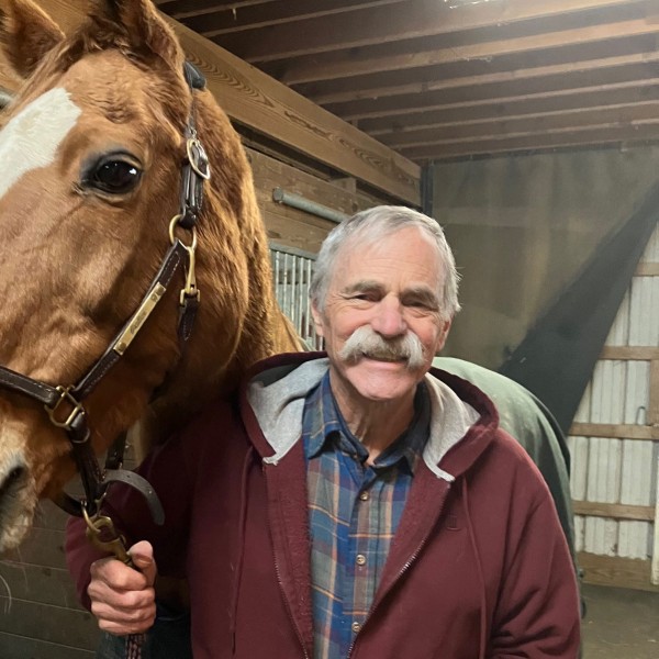 man in a barn with a horse