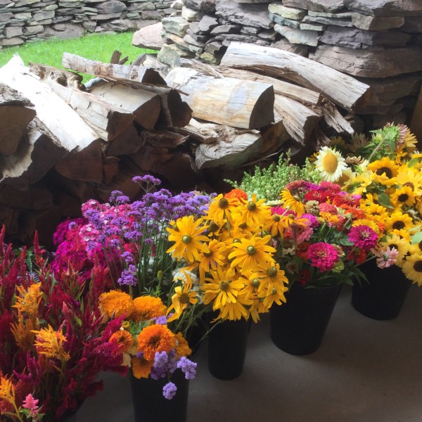 a colorful flower arrangement in front of stacked firewood