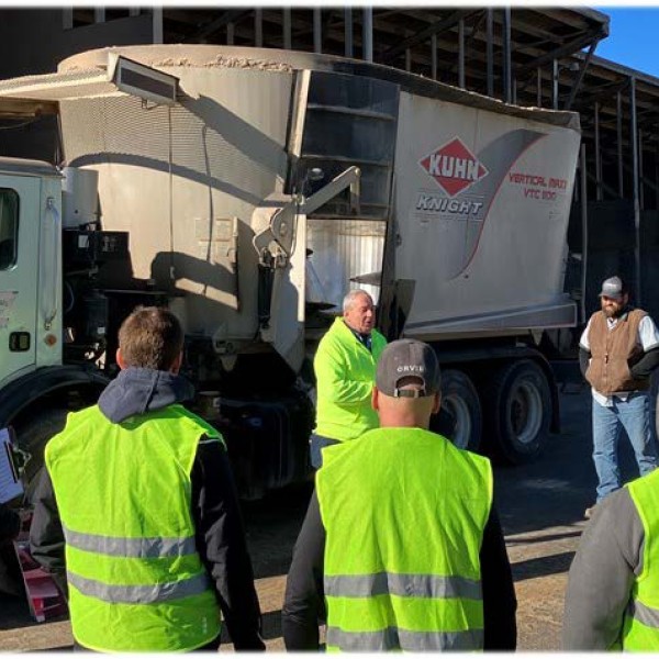 people standing around a dairy feed bunk