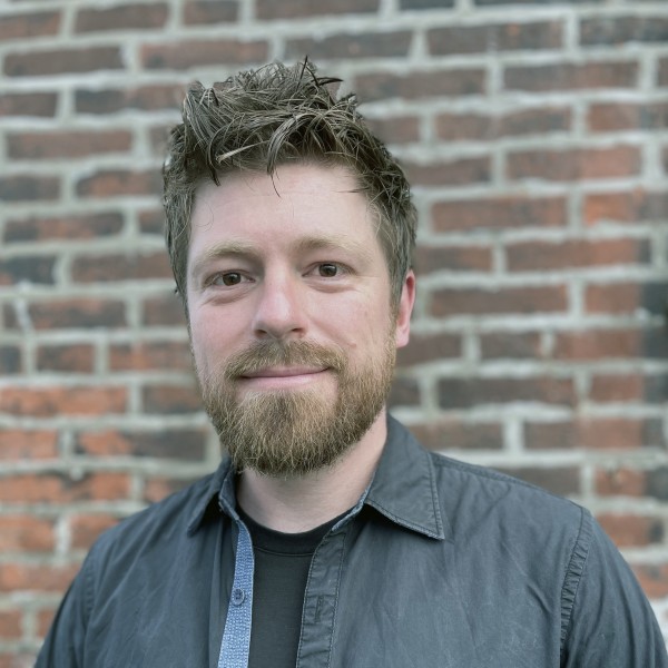 Nicholas Pevzner standing in front of brick wall