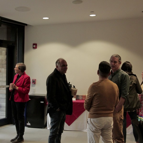 A group of people stand in front of buffet tables talking.