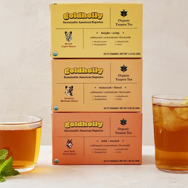 Three boxes of tea bags along with two cups of prepared tea. 