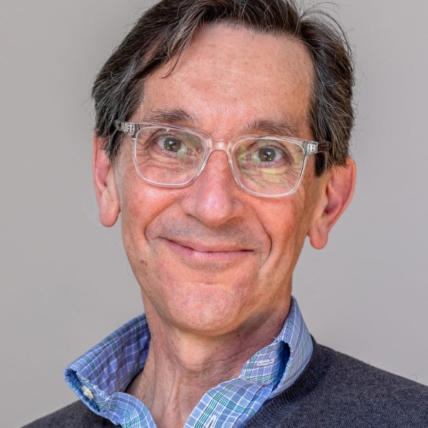 Professional portrait of a person wearing glasses, a blue shirt and grey sweater.