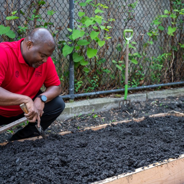 Kwesi Joseph at a raised bed, holding a trowel