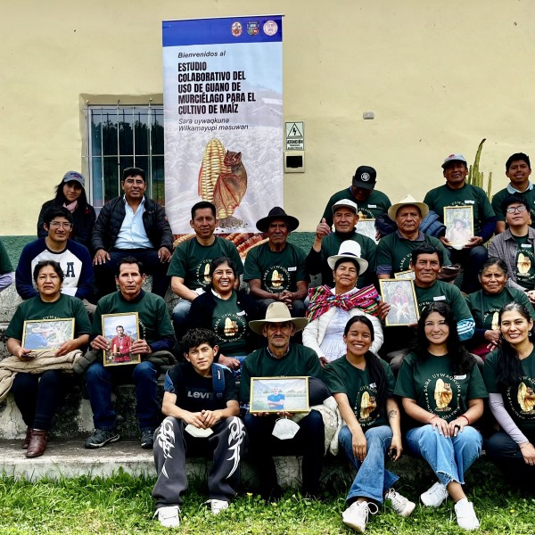 group of individuals smile for a picture in front of maize banner