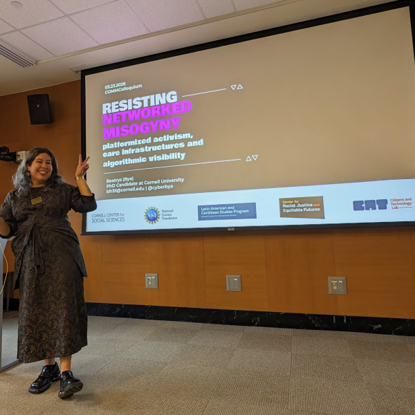 Beatrys Rodrigues presents on a stage in front of a screen