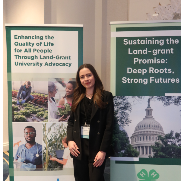 Kate Stephens ’26 posing next to banners at the CARET conference