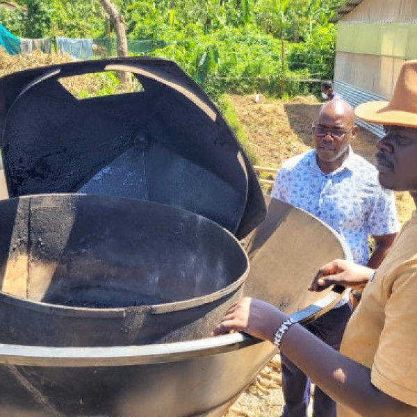 Charles Midega (left) and Roy Odawa display the Kontiki kiln they modified to make biochar from human feces. Credit: Rebecca Nelson