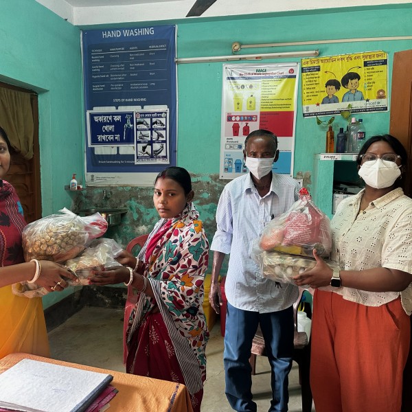 4 individuals stand holding groceries