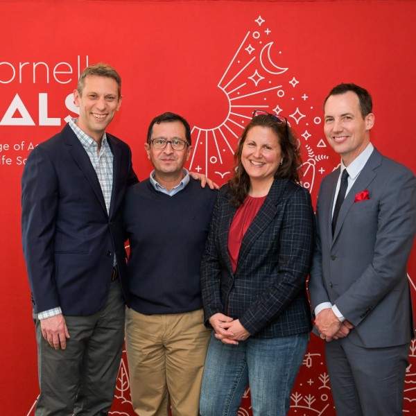 four people stand in front of a red background with the CALS logo on it
