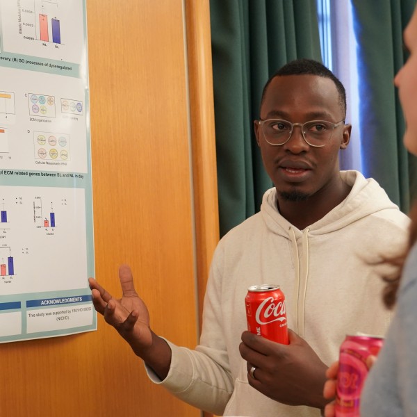 a man gestures at a poster on the wall as he talks to a woman