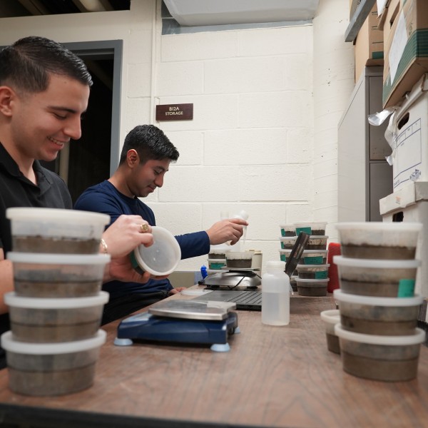 Two people work with scientific equipment on a desk.