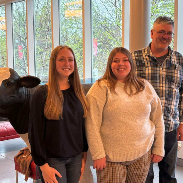 three people standing in front of a cow mode;