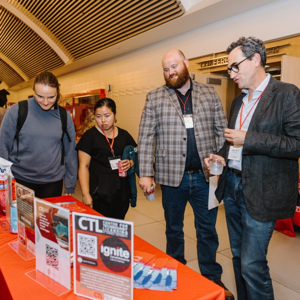 four people stand at a table with materials on it