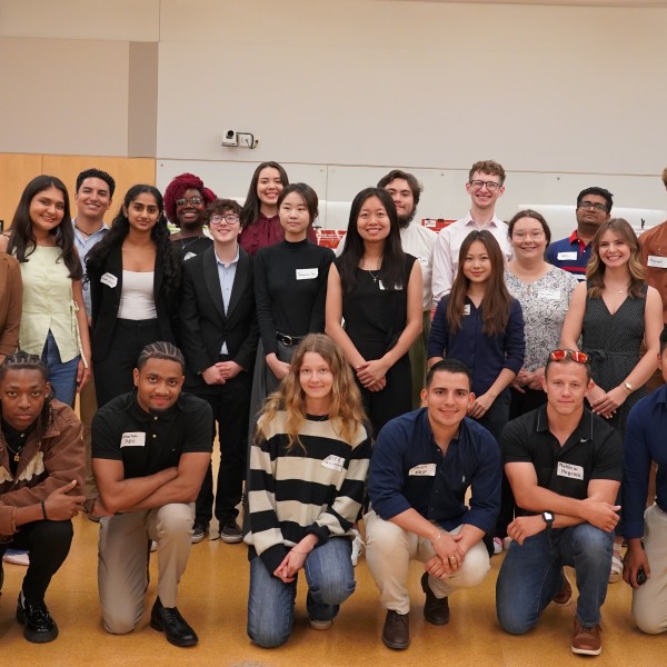 A group of people stand in two lines, each individual posing for the group photo.