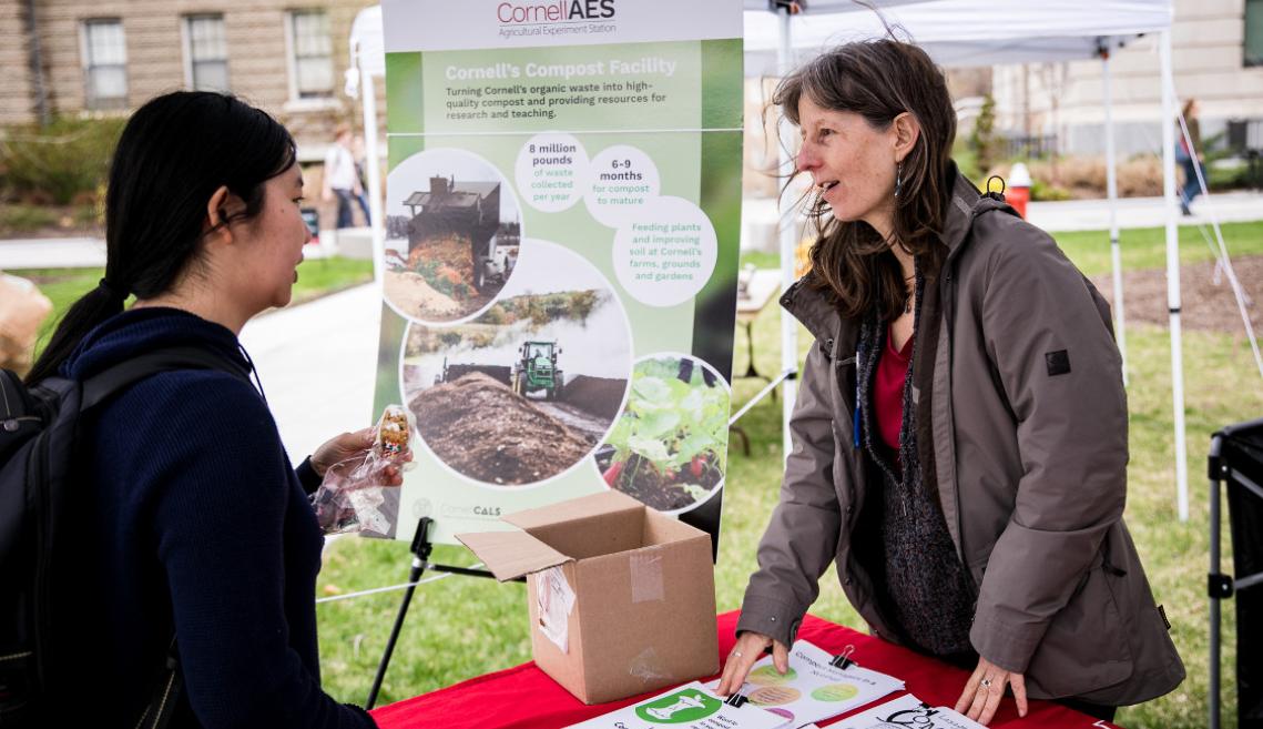 Two women talk to one another under a tent 