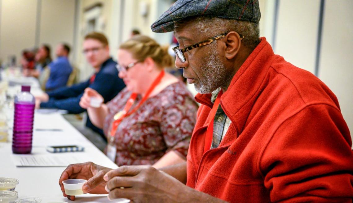A man sitting at a table sampling wine