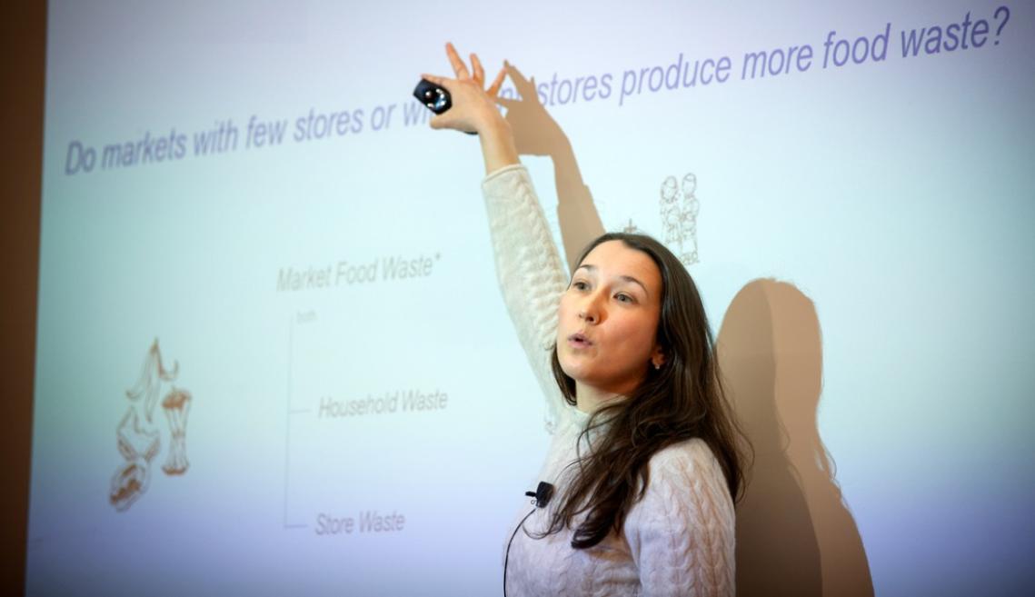 A woman standing in front of a projected image talking about the image