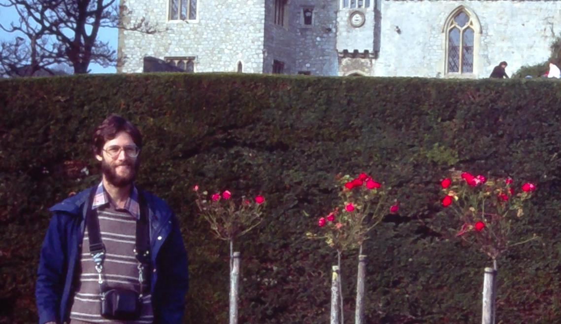 A man stands in front of a castle in the mid-1970s