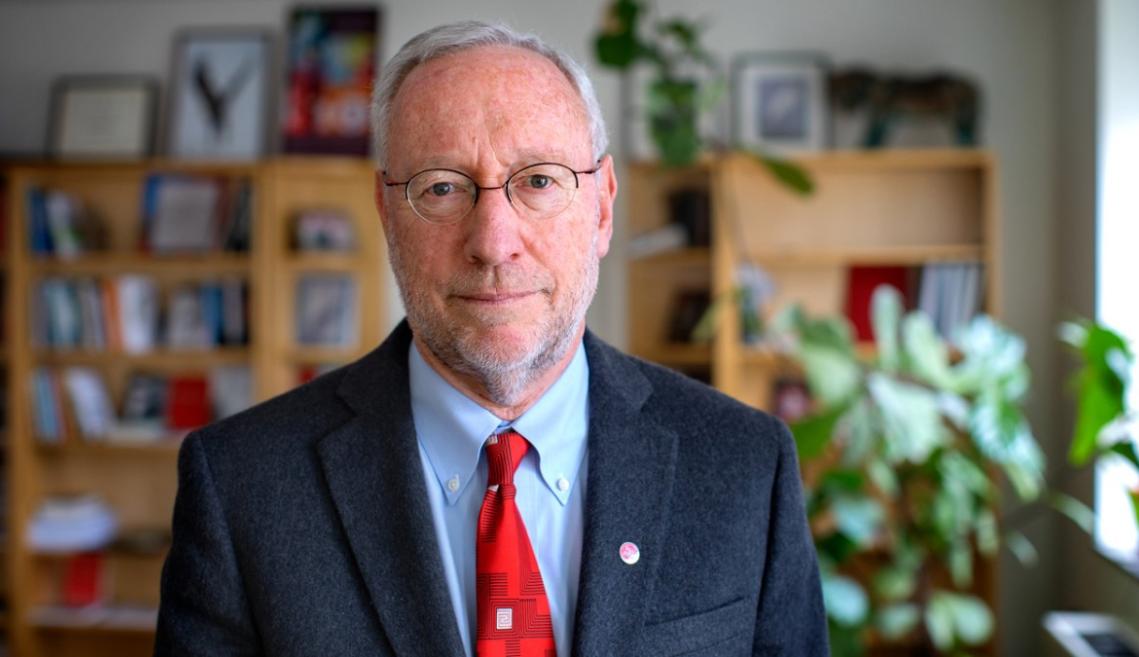 Man in suit and glasses smiles towards the camera