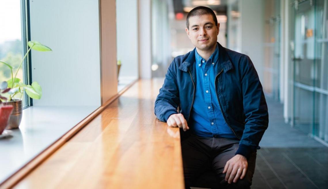 Man leans on a table glowing with sunlight peeking in from a window