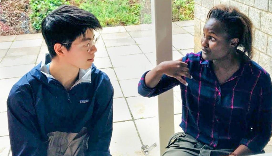 Two people sitting and talking to one another outside