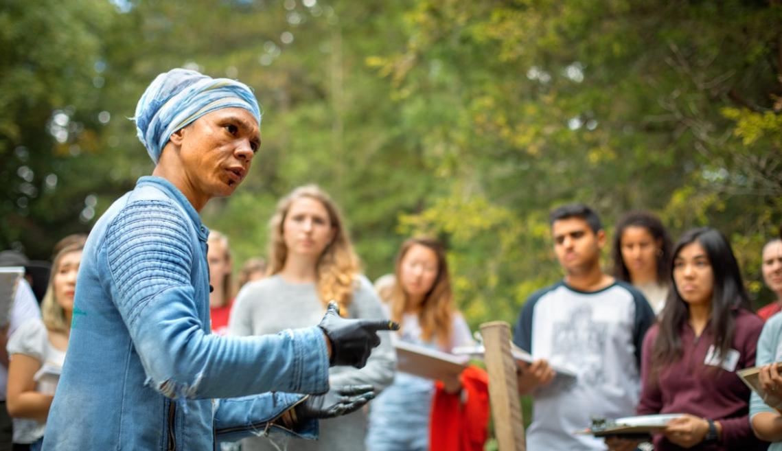 A male painter discusses with a group of students