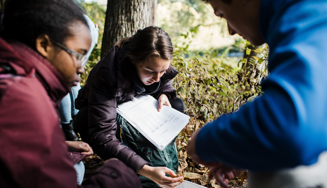 three students by a lake complete field research