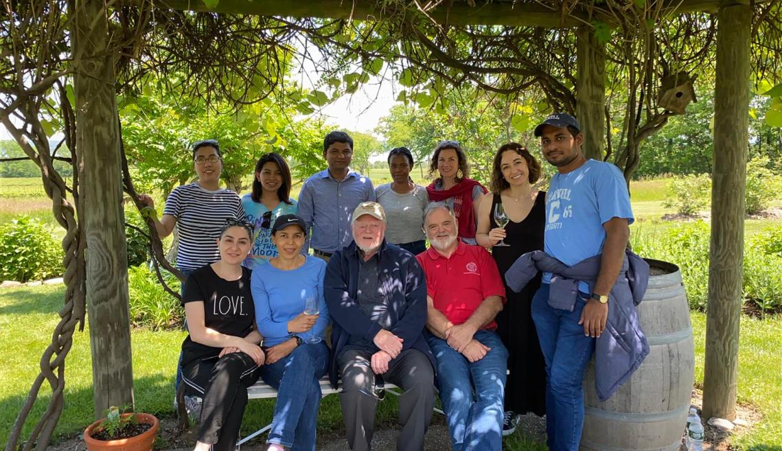 A group poses for a photo outside in a vineyard