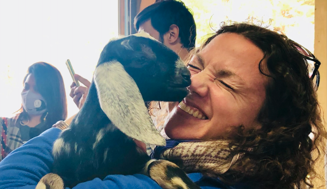 Woman laughs holding baby goat
