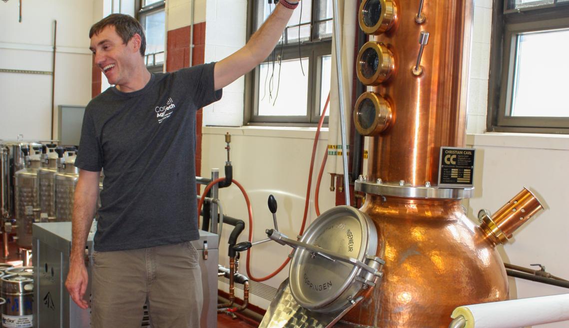 A man standing next to a copper still