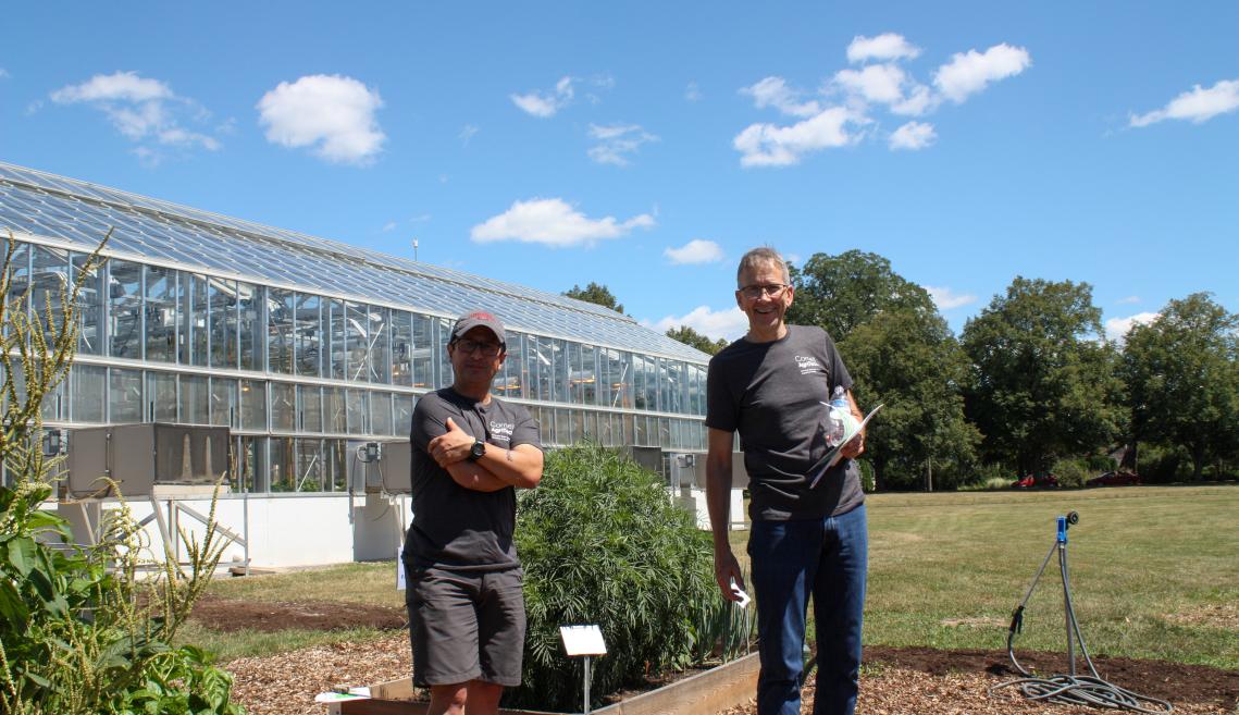 Two men wearing dark gray T-shirts standing outside