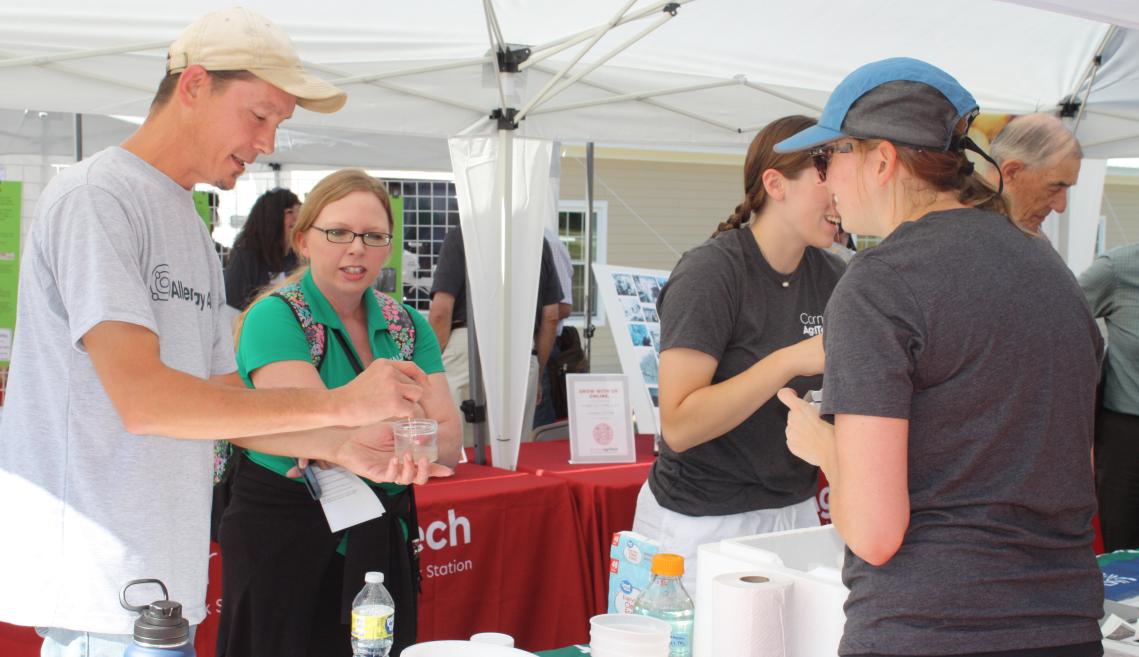Four people gathered together under a white tent.