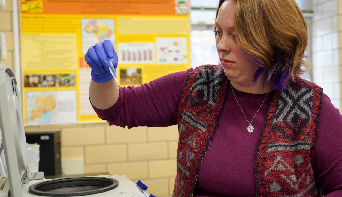 a woman holds up a vial in a lab