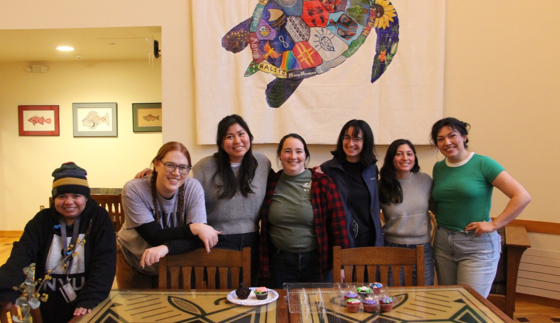 People stand in front of a table smiling.